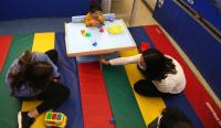 two occupational therapy students on a gym mat observing a child play with blocks